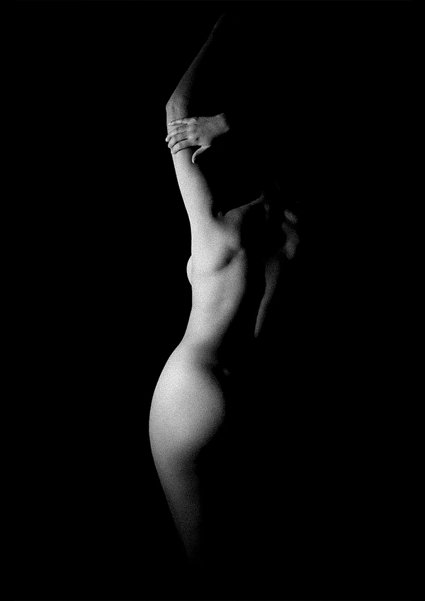 Black and white artistic photo of a nude woman from behind in darkness, illuminated to show silhouette, by Juan Pablo Galguera
